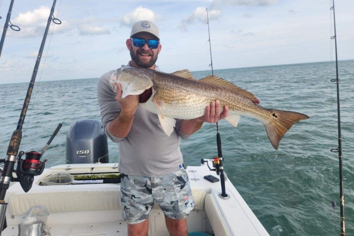 a man holding a fish on a boat in the water