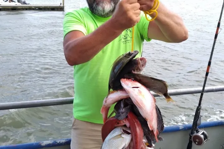 a man holding a fish on a boat in the water