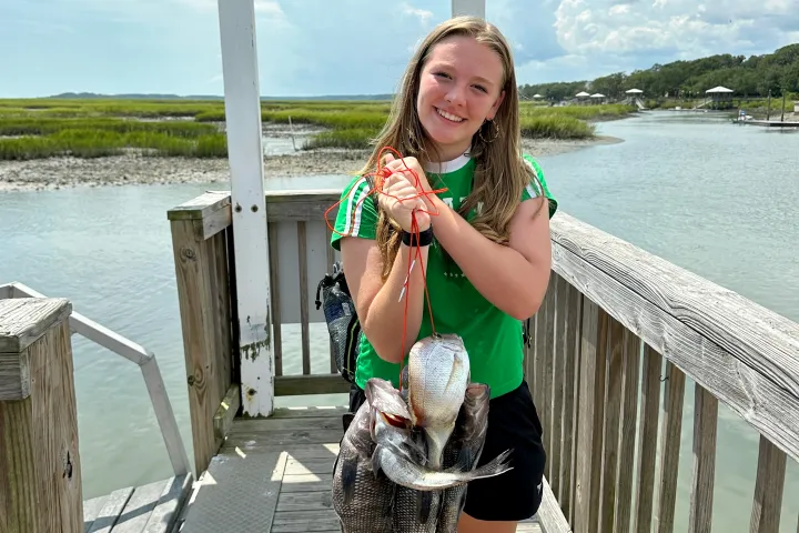 a girl holding a stringer of fish