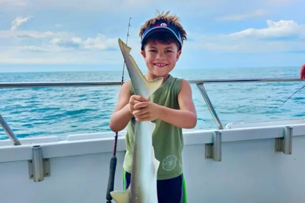 a young boy standing next to a body of water