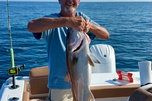 a man holding a fish on a boat in a body of water