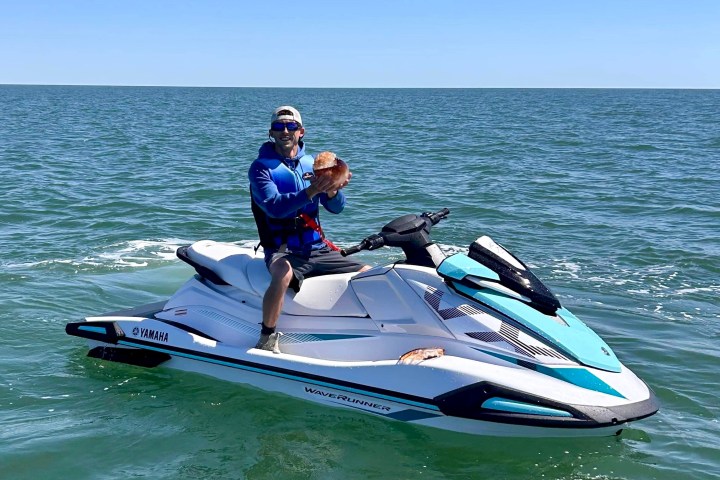 a man riding on the back of a boat in the water