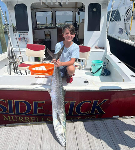 A Boy Holding A Fish On A Boat