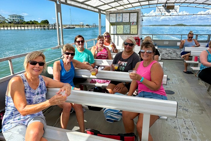 Group of people sitting on a boat with a covered roof on a sunny day.