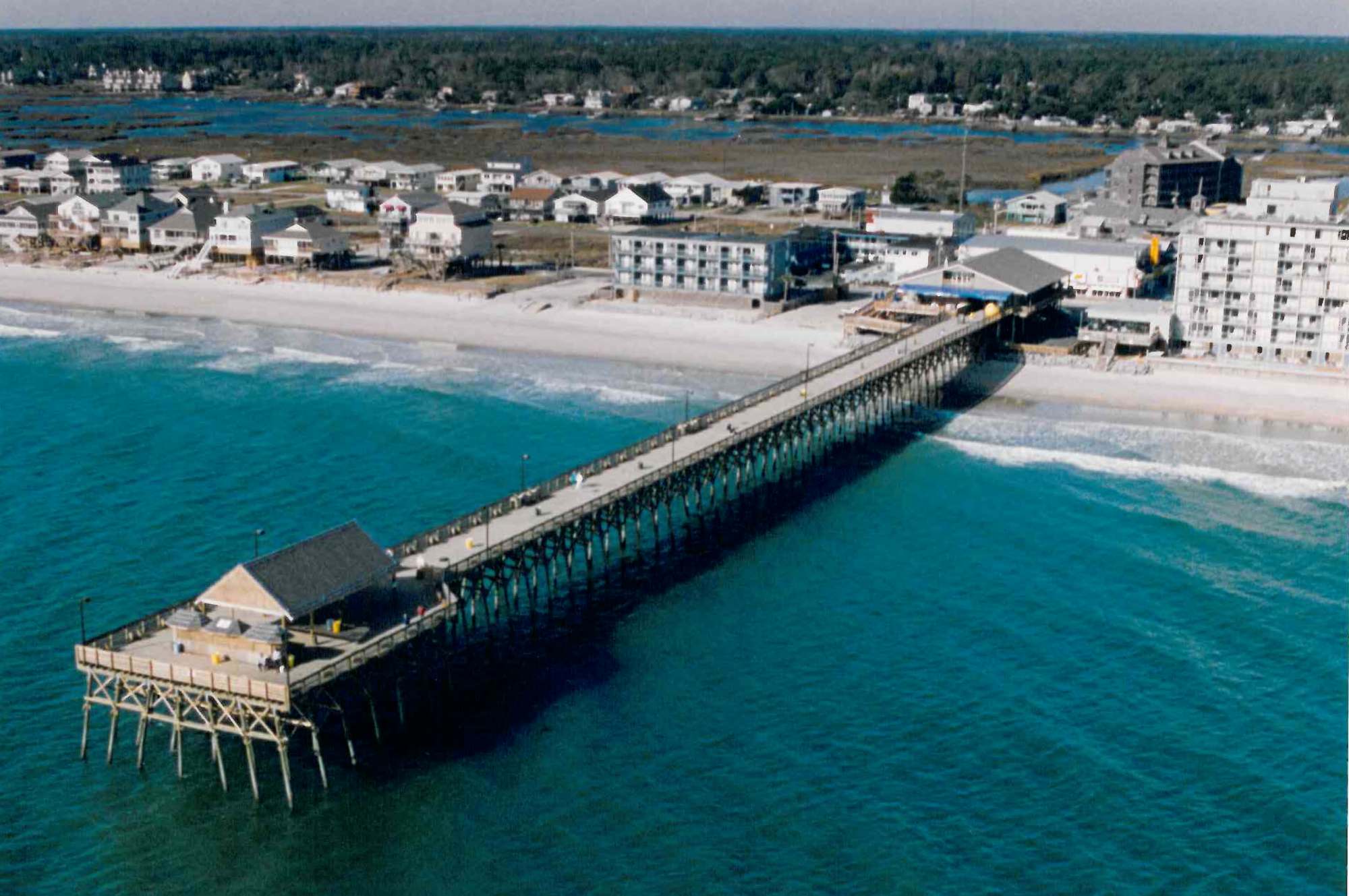 Garden City Pier Fishing South Carolina a body of water with a city in the background