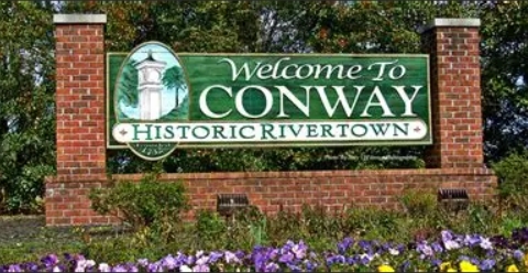 City of Conway South Carolina Brick sign reads 'Welcome to Conway Historic Rivertown' amidst greenery and flowers.