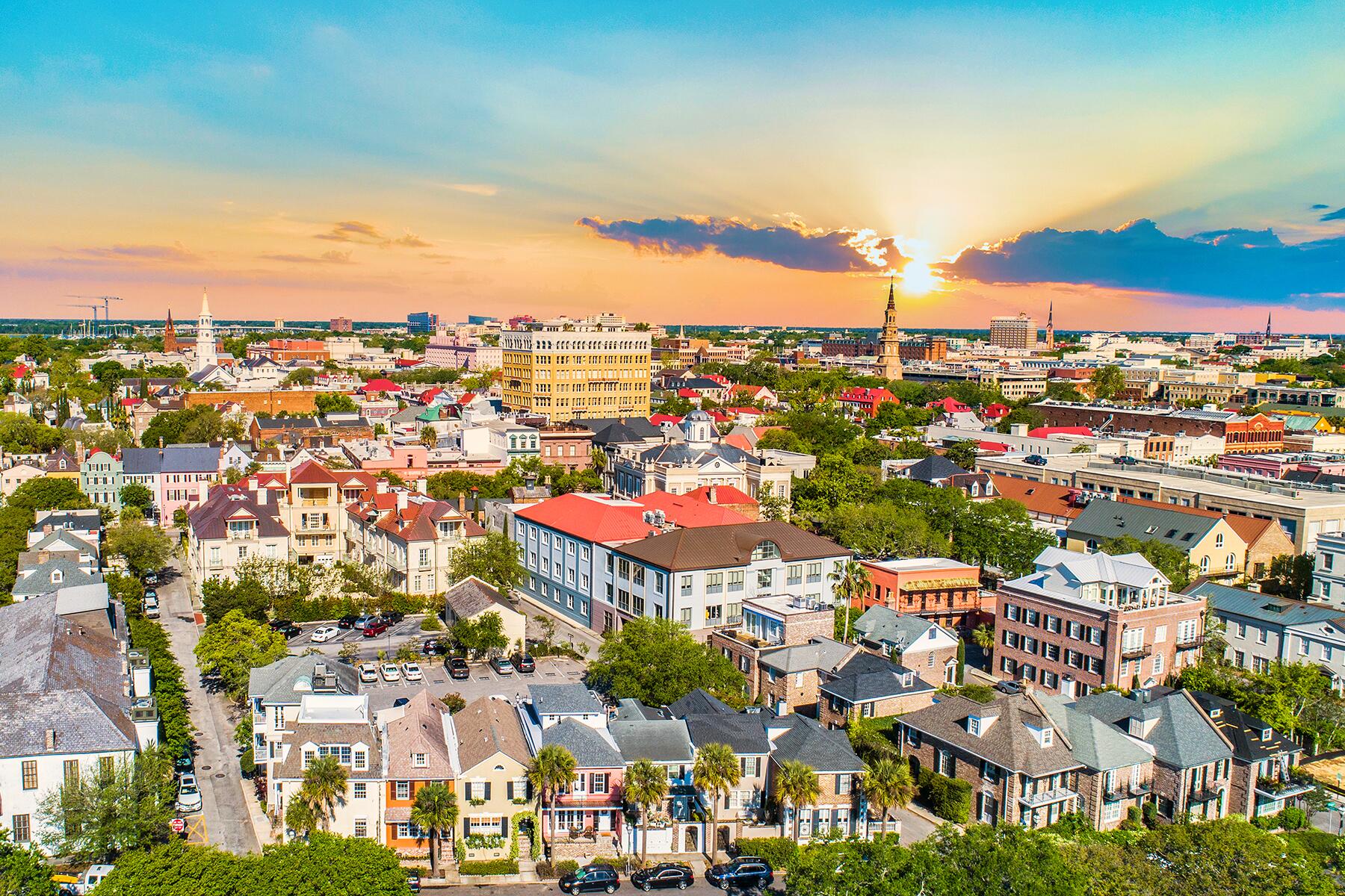 charleston south carolina Aerial view of a city with colorful buildings and a sunset sky.