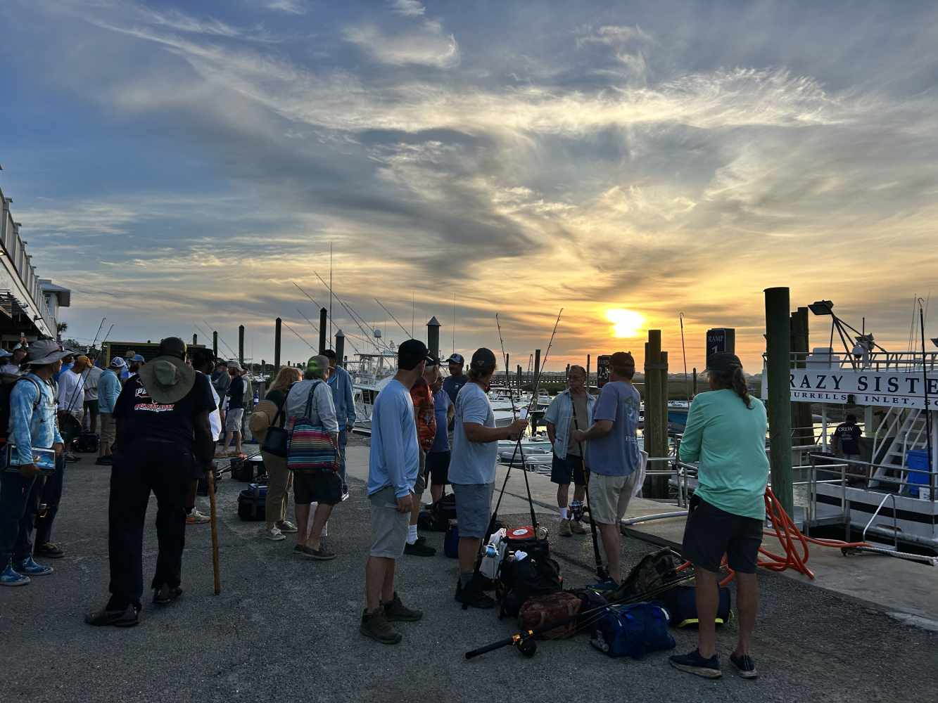 A group of people gathered on the doc with their fishing gear and bags for an overnight fishing trip in Murrells Inlet, South Carolina.