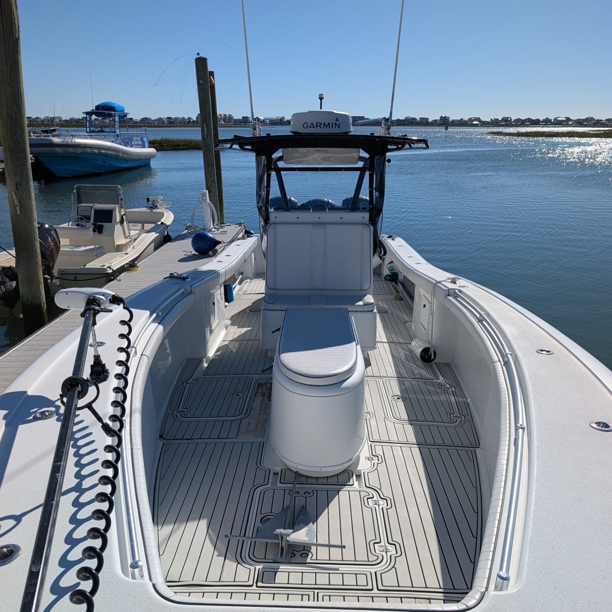 Interior of a white boat docked at a marina, with clear sky and water in the background.