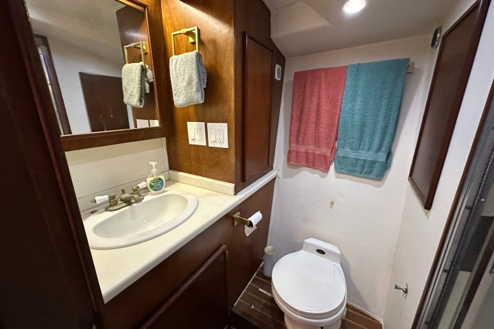 Small bathroom with a sink, toilet, and towels on wooden walls.