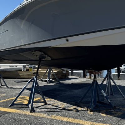 Boat on stands in parking lot with clear blue sky background.