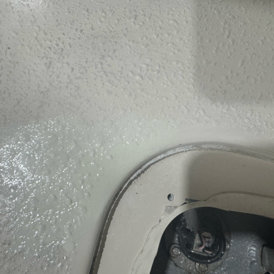 Close-up of textured, speckled white surface and a small dark circular opening.