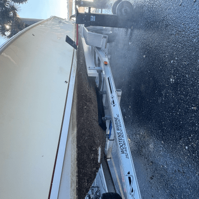 Boat on a trailer with a wet ground, palm trees in the background.
