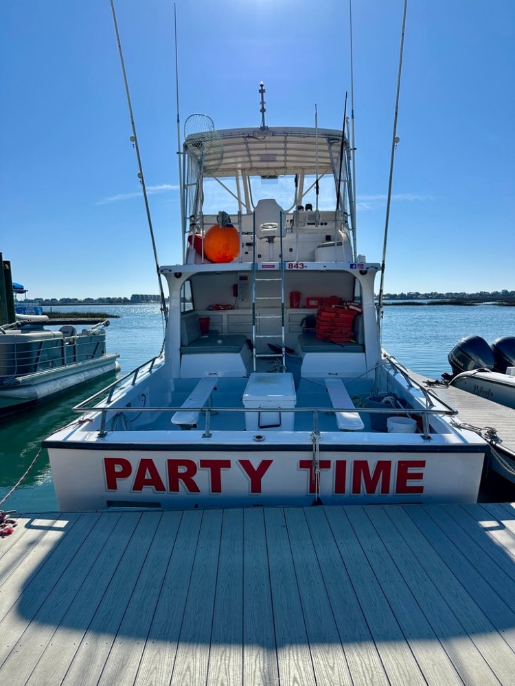 Rear view of a boat named 'Party Time' docked at a pier.