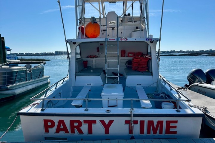 Rear view of a boat named 'Party Time' docked at a pier.