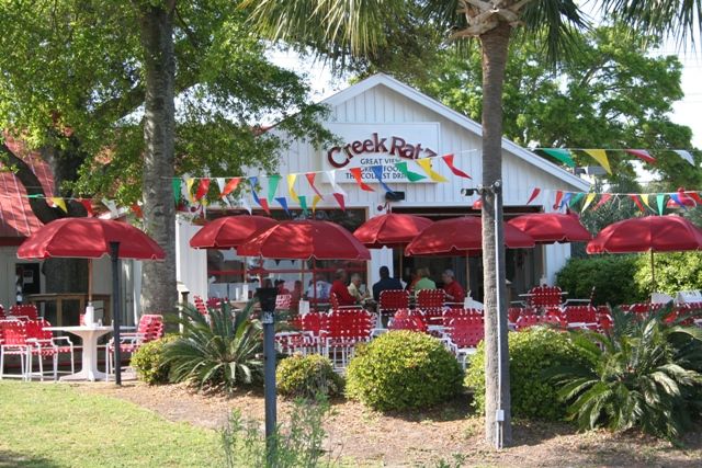 Outdoor seating at a restaurant with red umbrellas and canopy.