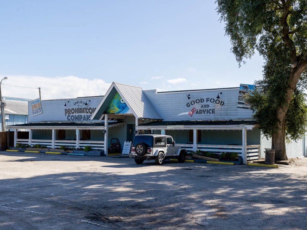 Exterior of a restaurant with a parked Jeep and painted murals.