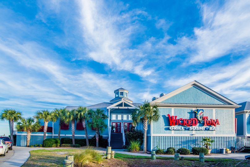 Blue restaurant with 'Wicked Tuna' sign, palm trees around.