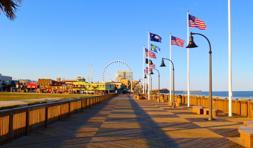 Boardwalk with flags and a Ferris wheel in the distance.