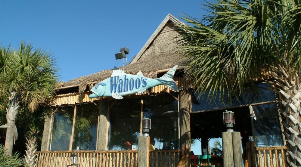 Tropical-themed restaurant with palm trees and a thatched roof.