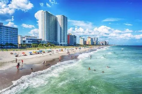 Beachfront cityscape with tall buildings and people enjoying the sandy shore.