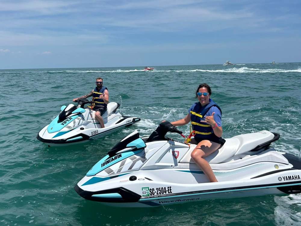Two people on jet skis in the ocean under a clear sky.